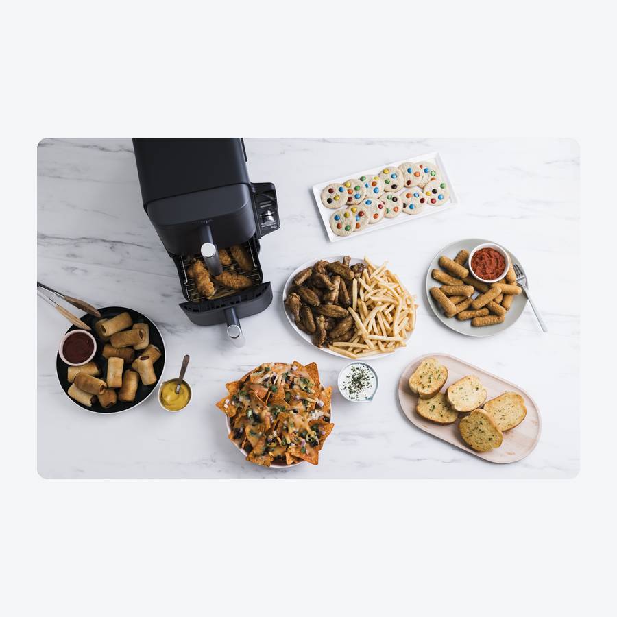 Ninja DoubleStack XL SL401 two-basket air fryer with both stacked drawers open beside plates of party food